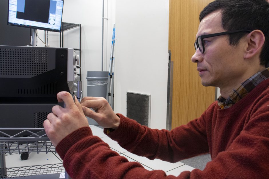 A man connects equipment to an electron microscope