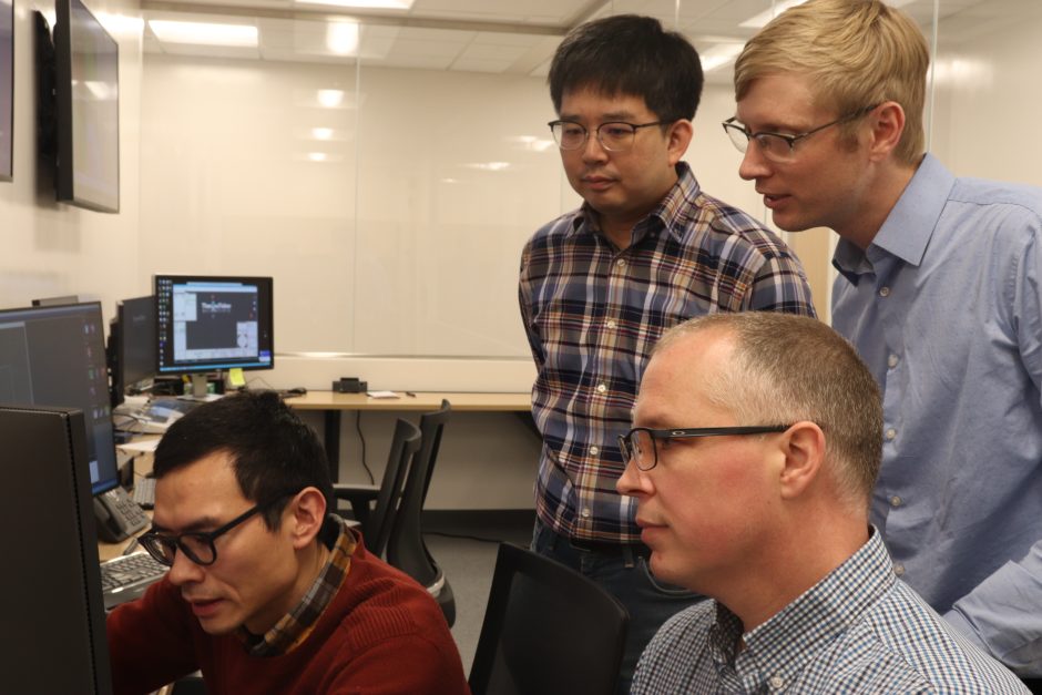 Four men look at a computer