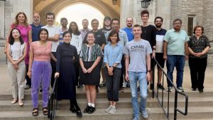 Students and faculty members stand on stairs and look at the camera