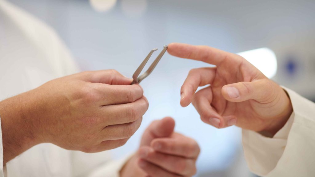 Fingers holding a u-shaped metal object