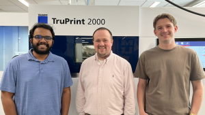 Ishfaqur Rahman, Scott Thompson and Talon Hanssen pose in front of a 3D metals printer